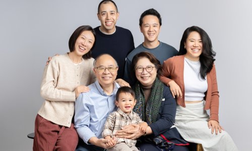 Newborn Photography Blog | Blossom Brook Studio 581 A warm Multigenerational Family Portrait featuring grandparents, parents, and a young child smiling together in a bright studio setting.