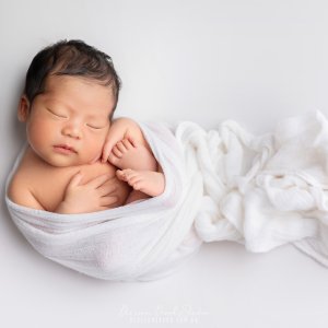 Newborn wrapped in soft white blanket.