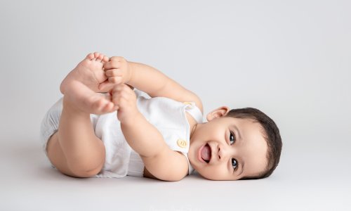 Newborn Photography Blog | Blossom Brook Studio 628 Smiling baby lying on back holding feet during a Sydney Baby Photography session at Blossom Brook Studio.
