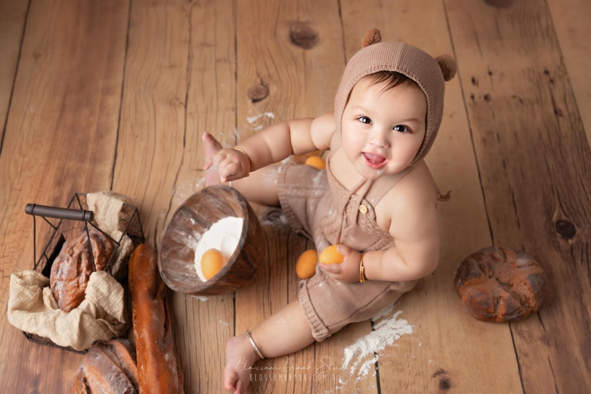 baby photos in sydney baby boy in bear costume on wooden floor