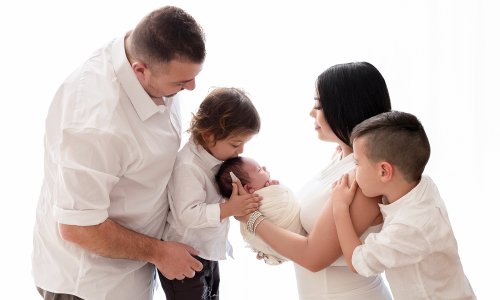 Newborn Photography Blog | Blossom Brook Studio 593 Family of five smiling and embracing their newborn baby during a bright, natural-light studio photoshoot in Sydney.