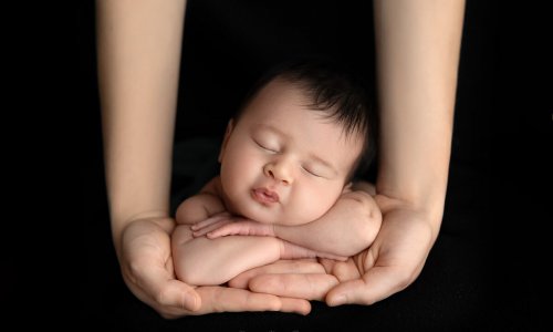 newborn baby photo on parents hands