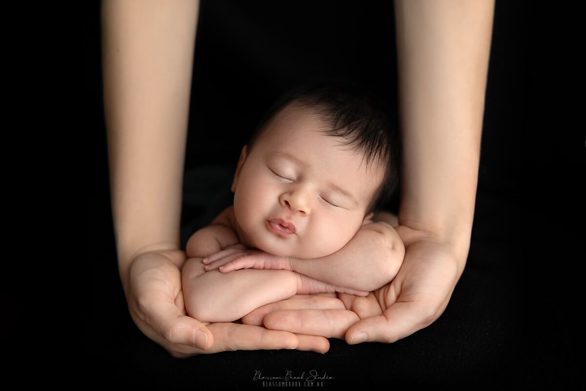 newborn baby photo on parents hands