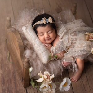 newborn baby girl sleep in a wooden bed smiling