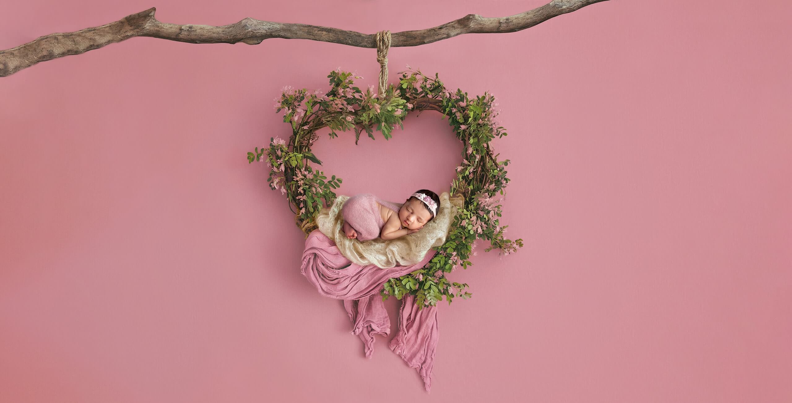 newborn photo baby sleep on hanging wreath pink back ground
