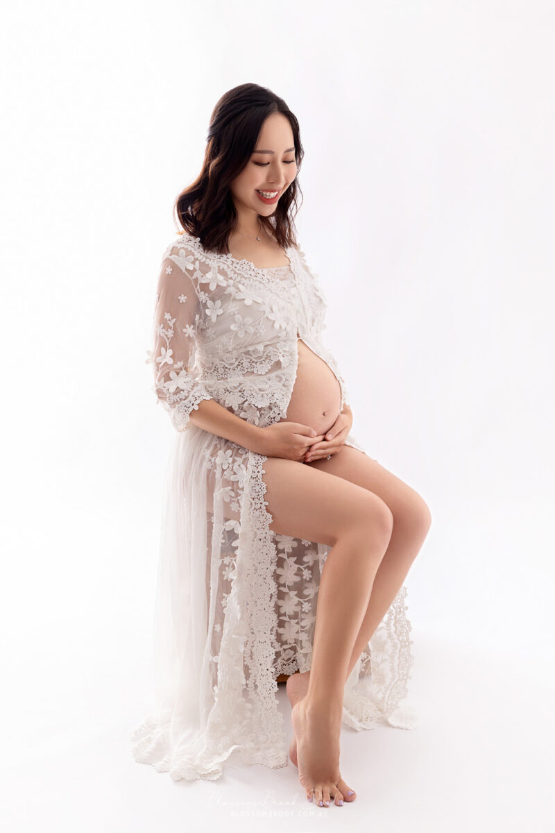 pregnant lady in white dress hold belly smile pregnancy shoot